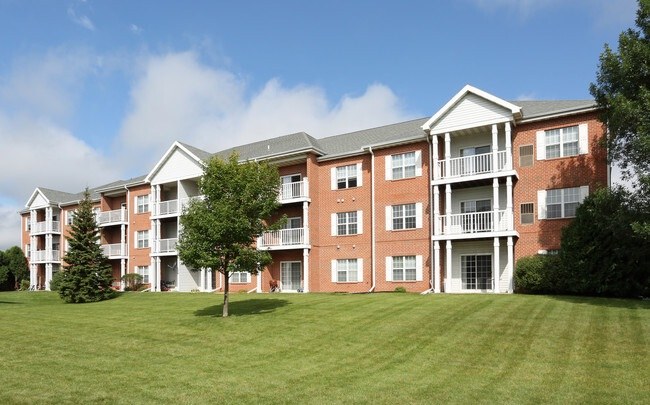 A large red brick apartment building with a green lawn in front.
